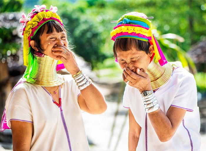Two Kayan long neck women laughing together at Baan Thong Luang iduring a Chiang Mai Photo Workshop, Thailand