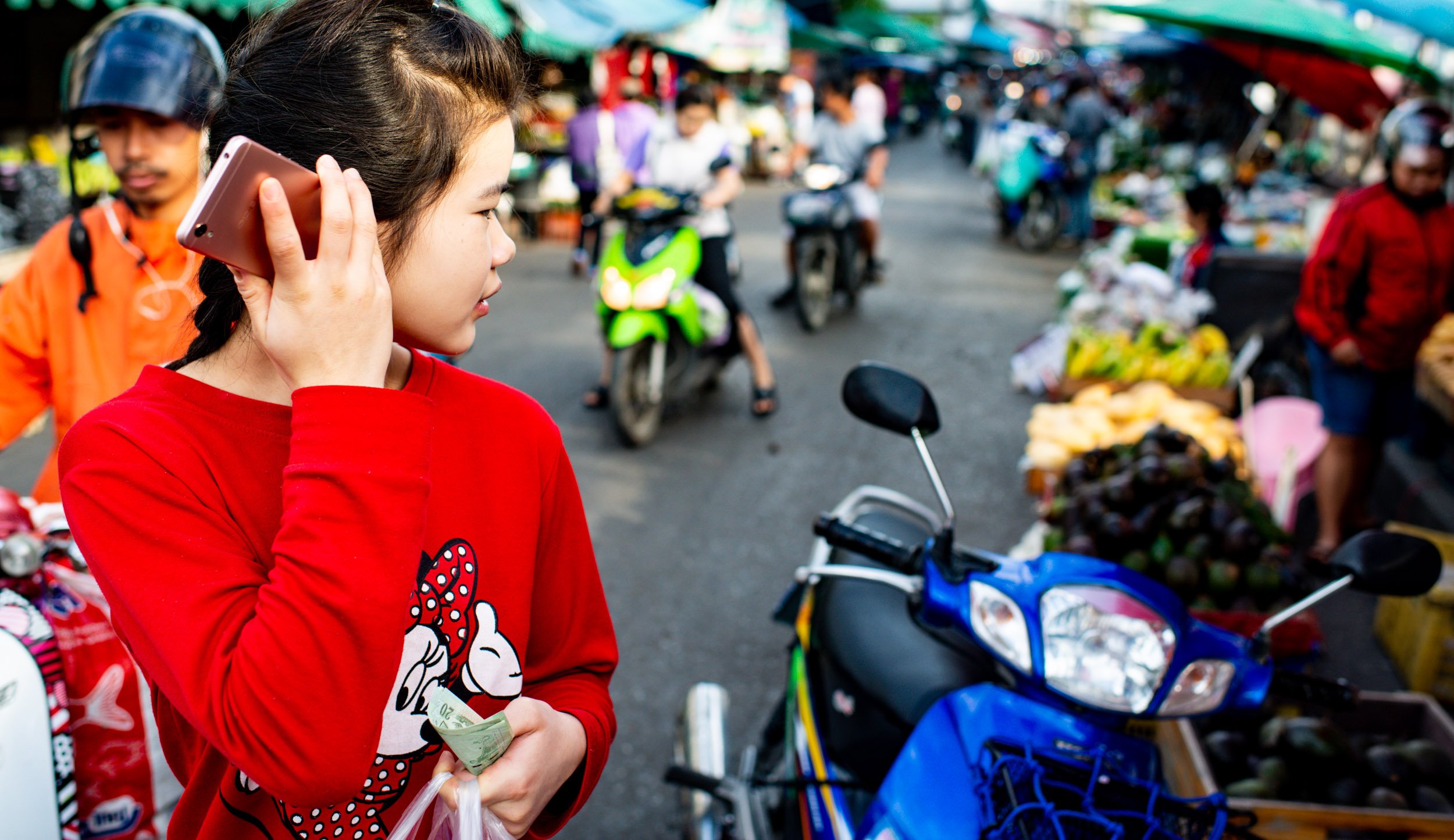 Young woman using a mobile phone at the market for Street Photography in Chiang Mai, © Kevin Landwer-Johan