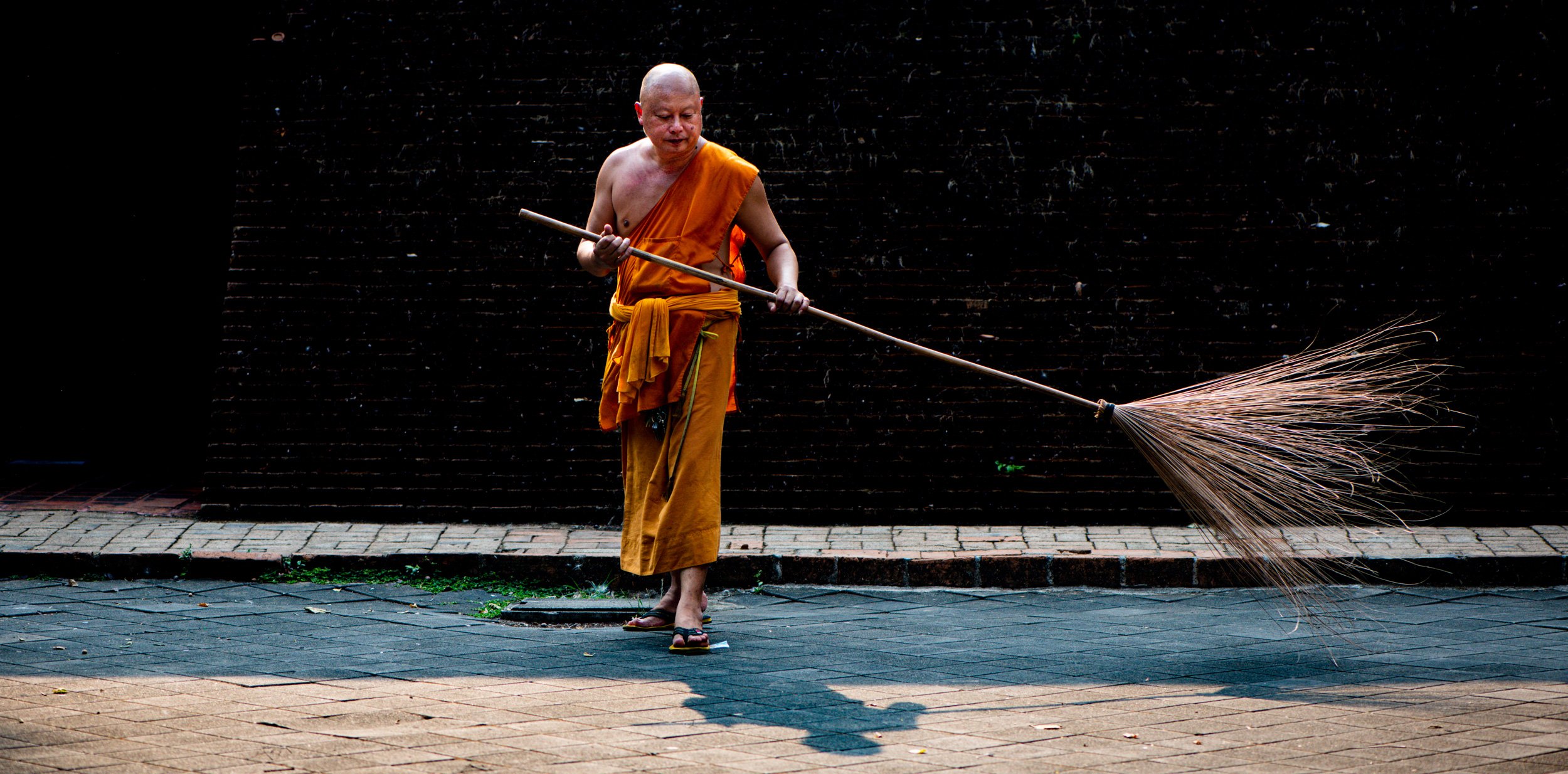 Buddhist monk sweeping the temple yard © Kevin Landwer-Johan